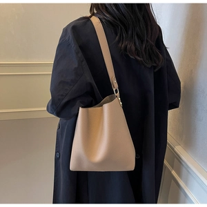 Detail of minimalist beige pebble leather bucket bag with metal ring strap connectors