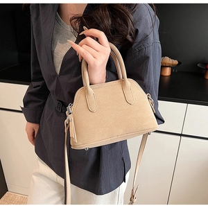 Close-up of beige lychee grain leather mini bag with silver studs and fine stitching