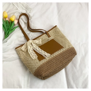 Detail of woven straw tote bag with lace bow, brown leather straps and floral accents