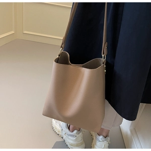 Close-up of litchi grain leather bucket bag with golden hardware on a shoulder strap