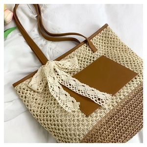 Detail of straw tote bag showing brown leather pocket and a large lace bow decoration