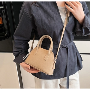 Detail of beige litchi grain mini crossbody bag with top handles and tassel zipper