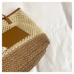 Close-up of woven straw tote bag featuring beige lattice texture and brown leather patch