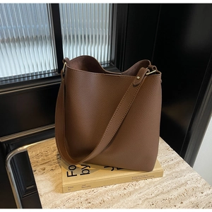 Close-up of deep brown lychee-textured leather bucket bag with gold stud hardware details