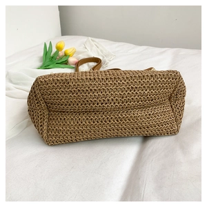Close-up of hand-woven straw tote bag with brown leather handles and flat bottom base