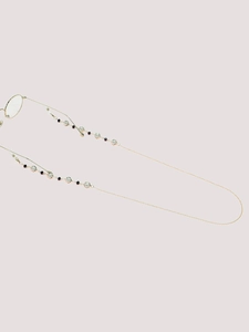 Detail of golden eyeglass chain with black beads and iridescent pearls on a soft background