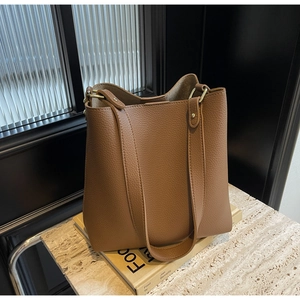 Detail view of brown pebbled leather tote bag with gold ring buckle and wide strap