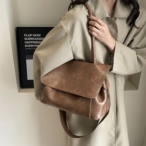 Große Retro-Tragetasche in Braun mit breitem Gurt, getragen zum beigen Trenchcoat