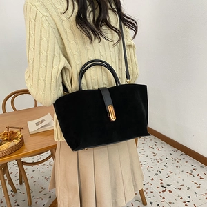 Large black suede tote bag with golden buckle shown in a stylish crossbody wear pose