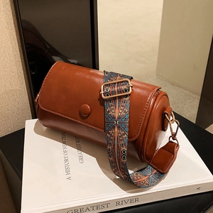 Brown cylinder crossbody pillow bag with vintage ethnic print wide strap and gold hardware