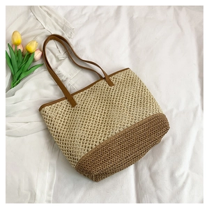 Detailed texture of two-tone woven tote bag with straw material and brown shoulder strap