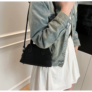 Detail of a black Boston style crossbody bag with litchi grain texture and metal feet