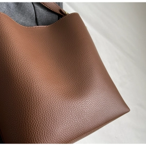 Close-up of caramel brown lychee leather texture and stitching on a tote bag