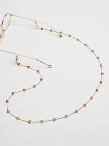 Détail d'une chaîne de lunettes dorée avec pendentifs cœur et boucles en silicone