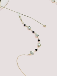 Detail of elegant eyewear chain with white pearls, black beads and gold-tone metal links