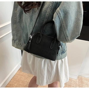 Detail of a black textured crossbody bag showing the adjustable strap and metal zipper
