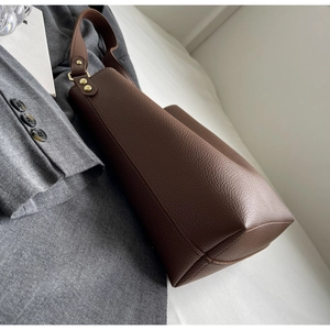 Detail of premium brown lychee grain leather tote bag with gold metal studs