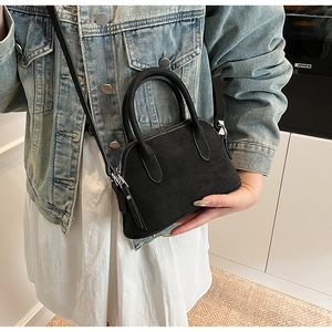 Close-up of black shell-shaped handbag with matte texture and dual top handles