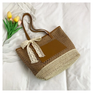 Detailed close-up of handmade straw tote bag with bicolor weave and lace bow decoration