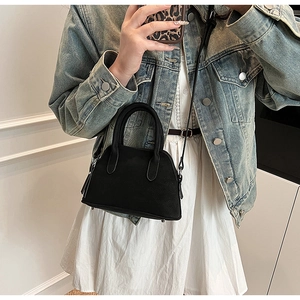 Detail of a minimalist black crossbody bag with silver hardware and adjustable strap