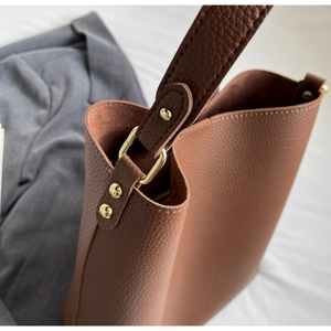 Detail of brown litchi pattern leather tote bag with elegant light gold metal hardware