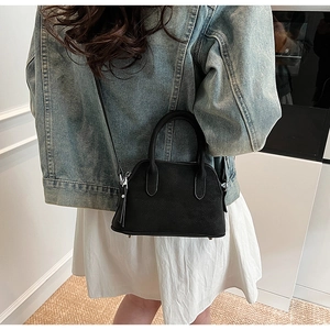 Model wearing a black shell-shaped handbag with premium lychee grain and shoulder strap