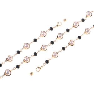 Elegant gold glasses chain with white pearls and black faceted beads on white background