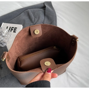 Brown pebbled leather tote bag with inner pouch on a grey suit jacket background