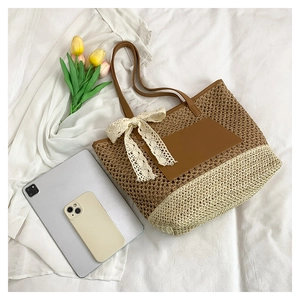 Detail of hand-woven tote bag with leather straps and a delicate white lace bow