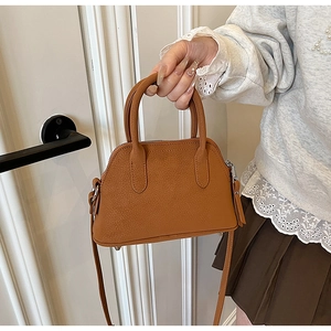 Detail of a caramel brown leather crossbody bag featuring vintage stitching and silver zipper