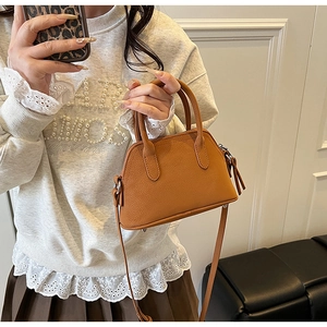 Close-up of brown litchi pattern leather mini handbag with adjustable strap and silver hardware