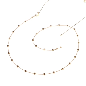 Détail d'une chaîne de lunettes dorée avec pendentifs en cœur et fermoirs mousqueton