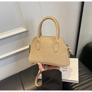 Detail of beige shell handbag with litchi grain leather texture and metallic bottom feet