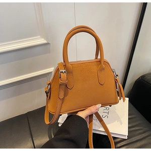 Detail of tan brown lychee grain faux leather handbag with metal zipper and sturdy handles