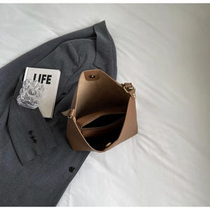 Detailed top view of brown pebble leather tote bag with inner pouch on soft white fabric