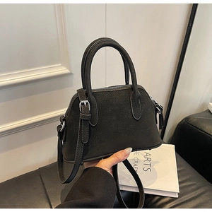 Detail view of black shell bag with matte texture and dual round top handles