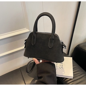 Close-up of black crossbody shell bag with silver hardware and wear-resistant bottom studs