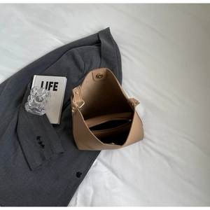 Detail of khaki tote bag showing magnetic clasp, zipper pocket, and leather texture
