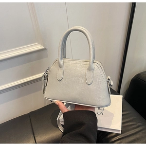 Detail of light grey lychee pattern leather shell bag with silver hardware and top handle