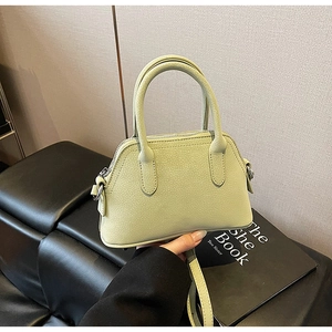 Close-up of light green lychee texture leather mini handbag with dual handles and strap