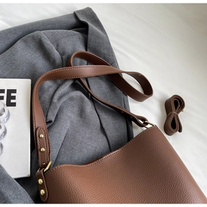 Detailed macro of brown lychee grain leather bucket bag with gold hardware and strap