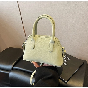 Macro detail of mint green shell bag featuring lychee grain texture and metal buckles