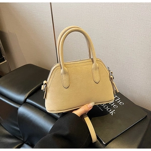 Close-up of beige lychee grain leather shell handbag with round handles and metal zipper