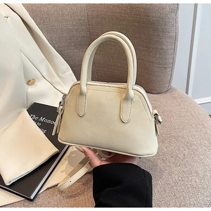 Detail of a creamy white lychee grain leather mini handbag with silver zipper and slim strap
