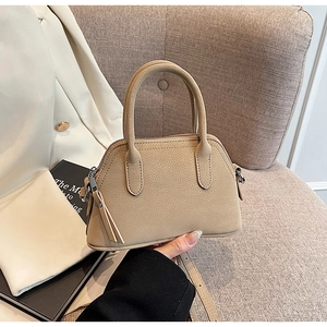 Close-up of pebble-textured leather handbag featuring metal hardware and top handles
