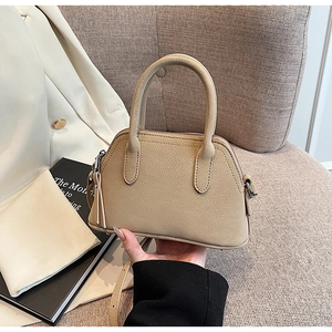 Detail of khaki dome handbag featuring pebbled texture and stylish tassel zipper pull