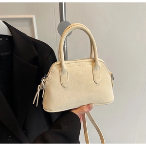 Detail of off-white mini boston bag with litchi grain texture and tassel zipper pull