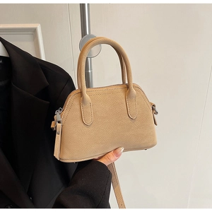 Detail of light beige crossbody bag with tubular handles and metallic zipper closure