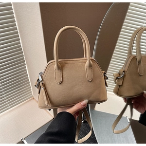 Detail of camel shell bag showing pebbled leather texture, dual handles and metal studs