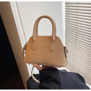 Detail of apricot Boston handbag with lychee pattern and protective bottom rivets